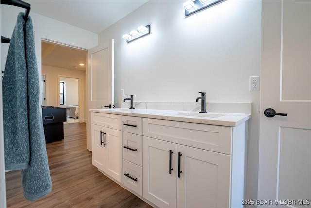 full bath with double vanity, a sink, and wood finished floors