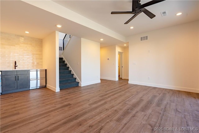 1152 Normandy Rd, Osage Beach, MO 65065 - unfurnished living room featuring bar with sink, recessed lighting, stairs, wood finished floors, and a ceiling fan
