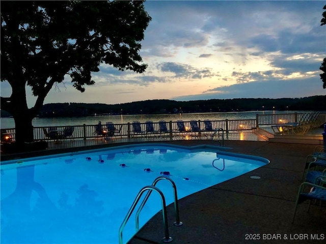 405 Barba Le Ln Unit 3B, Lake Ozark, MO 65049 - pool at dusk featuring a fenced in pool, a water view, and a patio area
