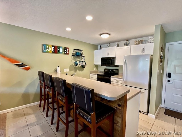 405 Barba Le Ln Unit 3B, Lake Ozark, MO 65049 - kitchen with a breakfast bar area, black electric range, freestanding refrigerator, a peninsula, and light tile patterned floors