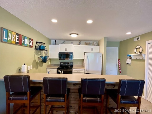 405 Barba Le Ln Unit 3B, Lake Ozark, MO 65049 - kitchen featuring white cabinets, light countertops, freestanding refrigerator, stainless steel microwave, and black range with electric stovetop