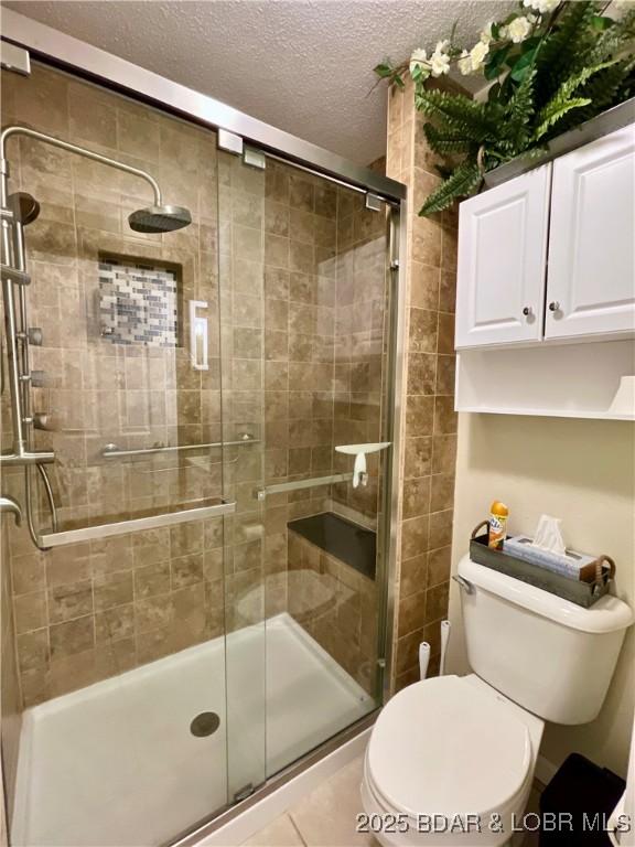 405 Barba Le Ln Unit 3B, Lake Ozark, MO 65049 - full bath featuring toilet, a textured ceiling, tile patterned floors, and a stall shower
