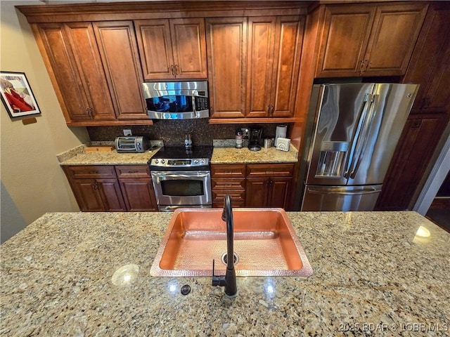 212 Weiskopf Way, Camdenton, MO 65020 - kitchen featuring stainless steel appliances, light stone counters, backsplash, and brown cabinetry