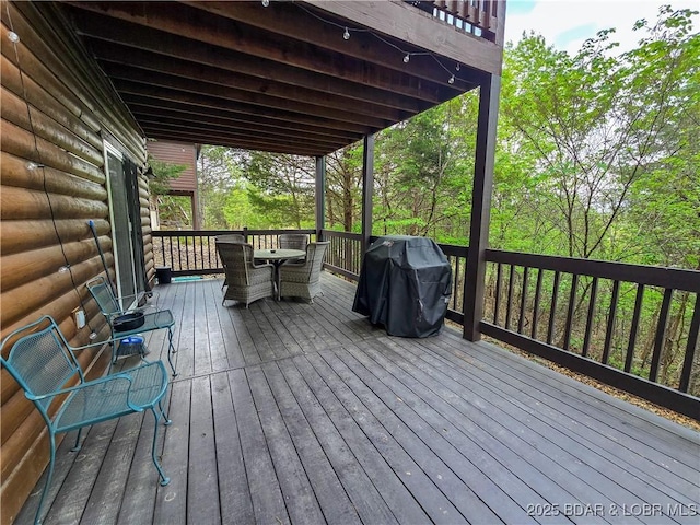 wooden terrace featuring outdoor dining area and grilling area