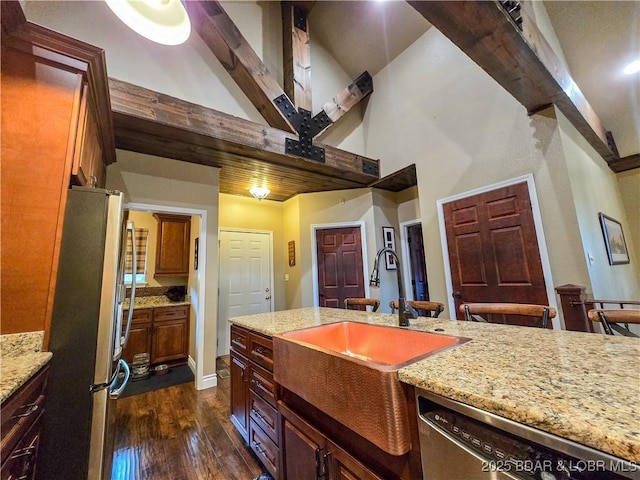 kitchen with dark wood-style flooring, appliances with stainless steel finishes, light stone counters, a sink, and high vaulted ceiling