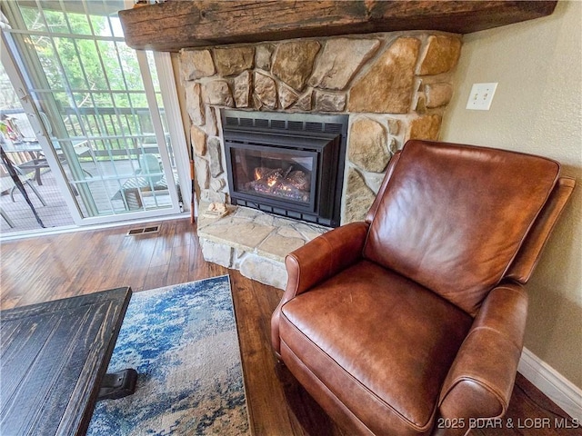 living area featuring baseboards, visible vents, wood finished floors, and a fireplace