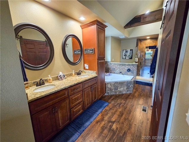 bathroom featuring a sink, a shower stall, a garden tub, and wood finished floors