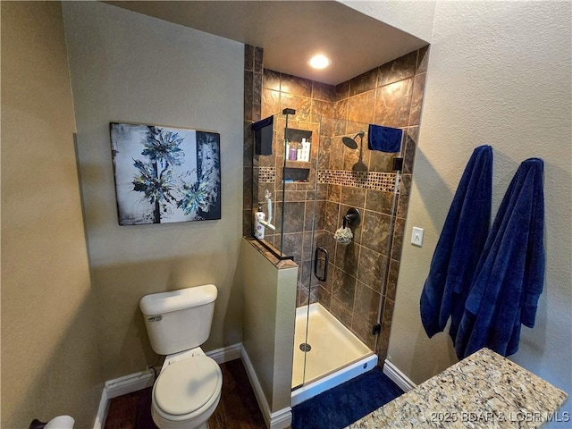 full bath with toilet, baseboards, a shower stall, and wood finished floors