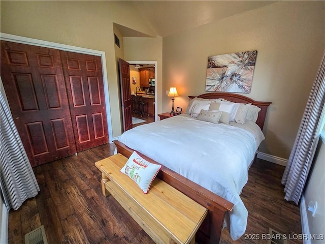 bedroom featuring visible vents, baseboards, wood finished floors, and vaulted ceiling