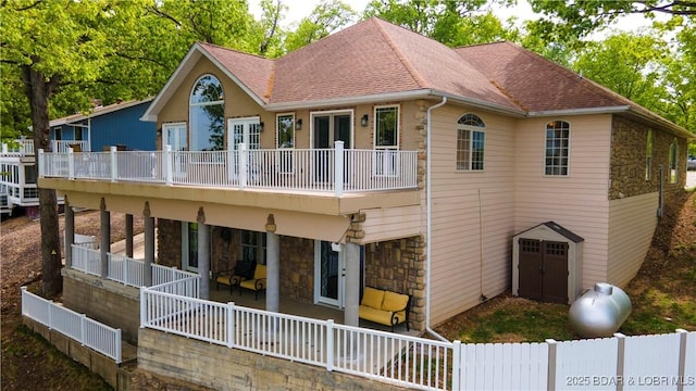 106 Bayliner Dr, Sunrise Beach, MO 65079 - rear view of house featuring stone siding, roof with shingles, and fence