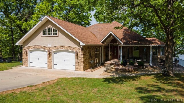 106 Bayliner Dr, Sunrise Beach, MO 65079 - view of front of property with a porch, stone siding, concrete driveway, a garage, and a front yard
