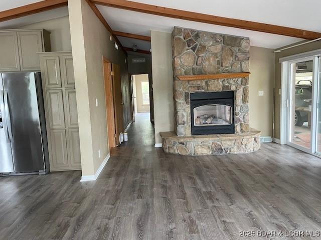 unfurnished living room featuring baseboards, lofted ceiling with beams, and wood finished floors