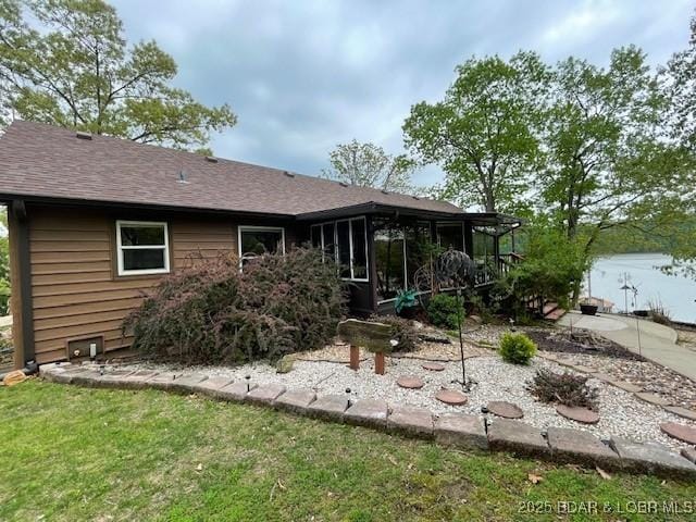 rear view of property featuring roof with shingles and a sunroom