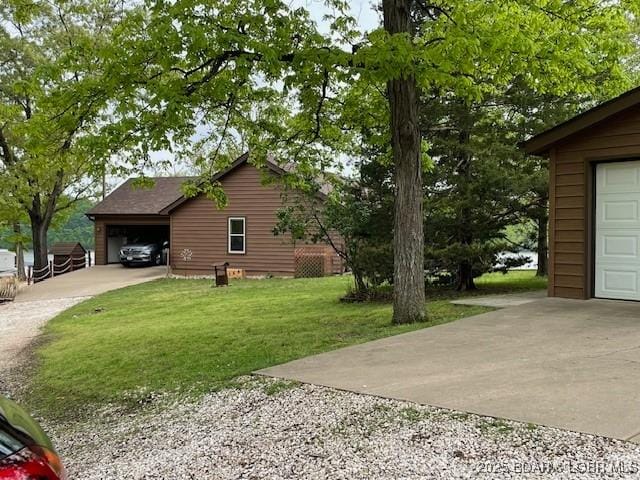 view of side of property featuring a lawn, driveway, and a garage