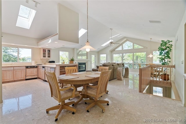 dining room with plenty of natural light, a ceiling fan, a glass covered fireplace, and a skylight