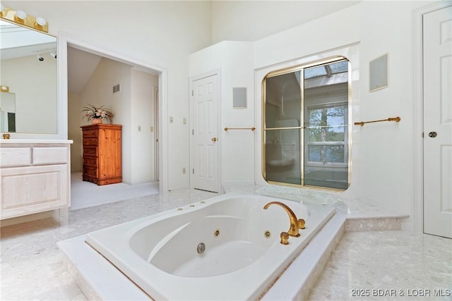 bathroom featuring a jetted tub, vanity, and visible vents
