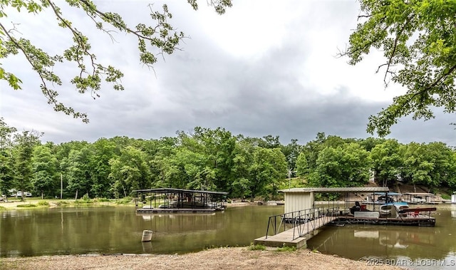 view of dock with boat lift, a water view, and a wooded view