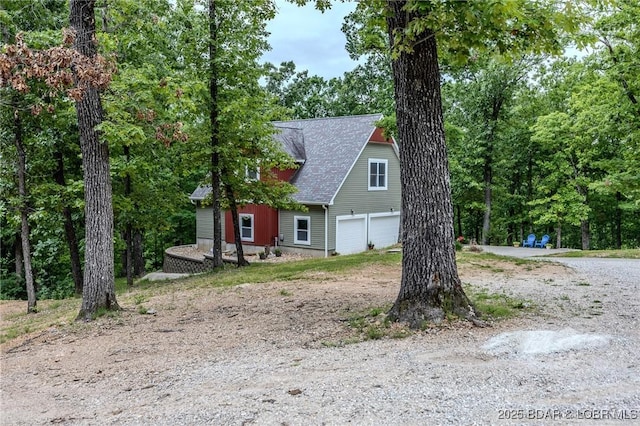 view of front of home featuring roof with shingles, an attached garage, and driveway