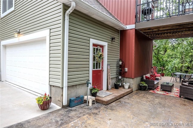 property entrance with a garage, driveway, a patio area, and outdoor lounge area
