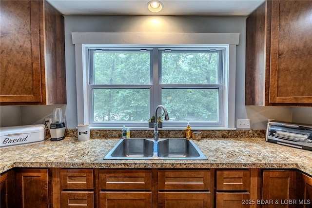 kitchen featuring plenty of natural light, a sink, brown cabinets, and light countertops