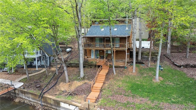 back of property featuring a shingled roof, a deck with water view, and stairway