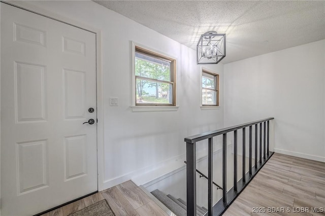 interior space with baseboards, a textured ceiling, an inviting chandelier, and wood finished floors