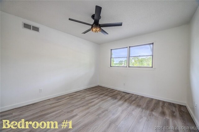 empty room featuring baseboards, a ceiling fan, wood finished floors, and visible vents