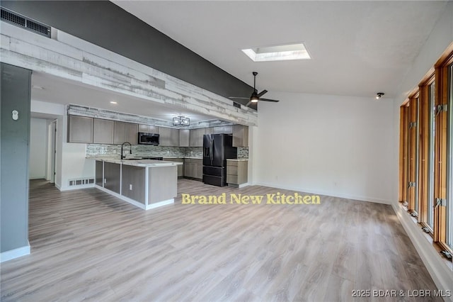 kitchen with visible vents, a peninsula, black refrigerator with ice dispenser, light countertops, and stainless steel microwave