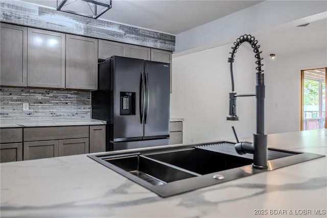 kitchen featuring light countertops, decorative backsplash, and stainless steel fridge with ice dispenser