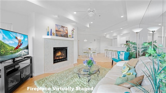 72 Emerald Bay Dr Unit 2D, Lake Ozark, MO 65049 - living room featuring a tile fireplace, a raised ceiling, a ceiling fan, recessed lighting, and light wood-type flooring