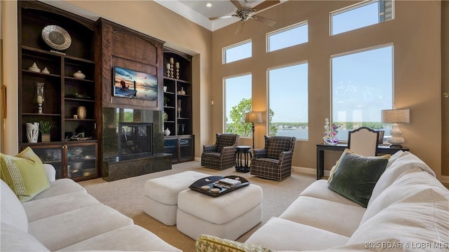 559 Forestridge Ln, Sunrise Beach, MO 65079 - carpeted living room featuring a ceiling fan, a high end fireplace, ornamental molding, and a towering ceiling