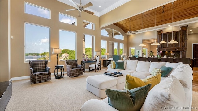 559 Forestridge Ln, Sunrise Beach, MO 65079 - living room featuring a ceiling fan, a towering ceiling, baseboards, ornamental molding, and carpet