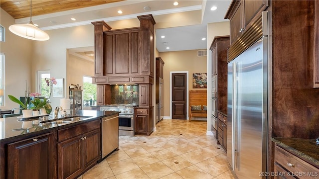 559 Forestridge Ln, Sunrise Beach, MO 65079 - kitchen featuring high quality appliances, a sink, dark stone counters, decorative light fixtures, and light tile patterned floors
