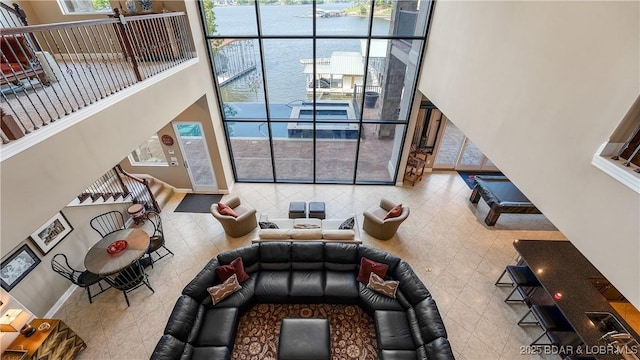559 Forestridge Ln, Sunrise Beach, MO 65079 - sunken living room with a towering ceiling, a water view, a wall of windows, tile patterned flooring, and baseboards