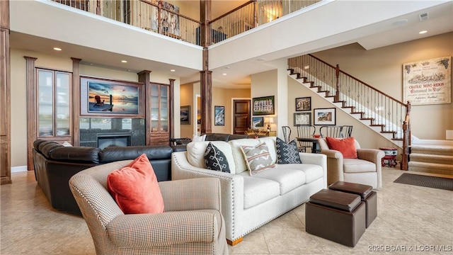 559 Forestridge Ln, Sunrise Beach, MO 65079 - living room with tile patterned floors, a towering ceiling, stairway, a glass covered fireplace, and recessed lighting