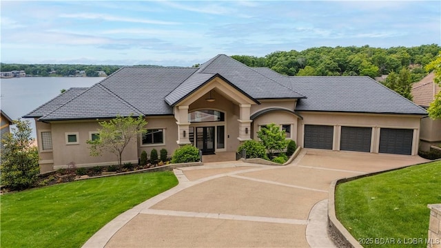 559 Forestridge Ln, Sunrise Beach, MO 65079 - french country home featuring stucco siding, an attached garage, a front yard, and concrete driveway