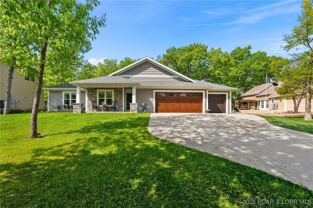view of front of property featuring a garage, stone siding, driveway, and a front yard
