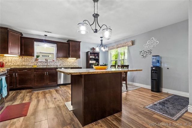 kitchen featuring decorative backsplash, a kitchen island, wood finished floors, and dishwasher