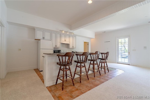 188 Bur Oaks Rd, Camdenton, MO 65020 - kitchen with freestanding refrigerator, light carpet, and a kitchen bar