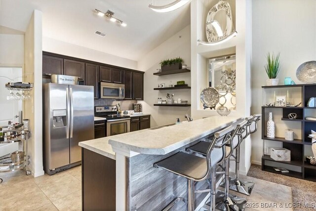 62 Knox Rd Unit 503, Rocky Mount, MO 65072 - kitchen with open shelves, dark brown cabinets, light countertops, lofted ceiling, and stainless steel appliances