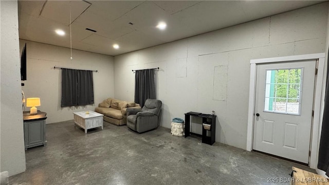 living room with recessed lighting, attic access, and concrete floors
