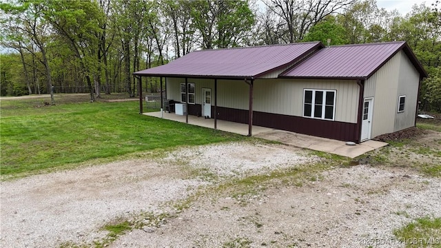 view of property exterior with a patio, fence, a yard, and metal roof