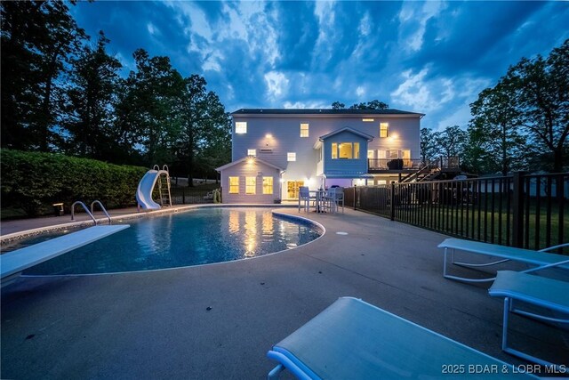 view of swimming pool featuring a diving board, a patio area, fence, a fenced in pool, and a water slide
