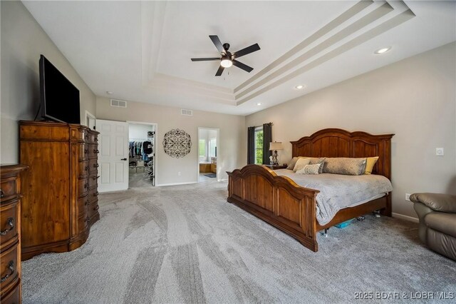 bedroom with a raised ceiling, baseboards, and light carpet