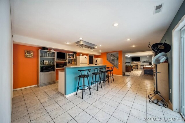 kitchen featuring freestanding refrigerator, a breakfast bar, recessed lighting, and visible vents