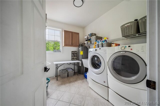 laundry area with laundry area, water heater, light tile patterned flooring, and washer and dryer