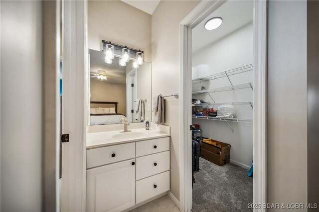 bathroom featuring baseboards, a spacious closet, ensuite bathroom, and vanity