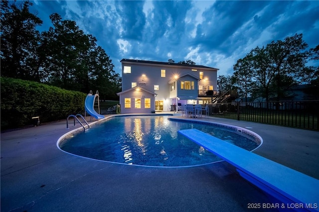 view of pool with a diving board, fence, a fenced in pool, a patio, and a water slide