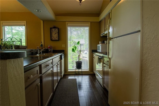362 Hopetown Dr, Osage Beach, MO 65065 - kitchen featuring a healthy amount of sunlight, dark countertops, a sink, a textured wall, and white appliances