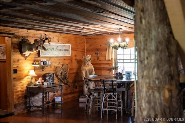 dining space featuring a chandelier, wooden walls, and wood finished floors